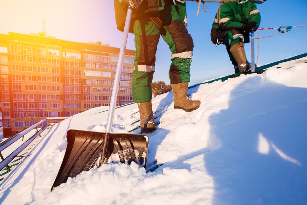 Roof after a blizzard with two people shoveling snow off of it
