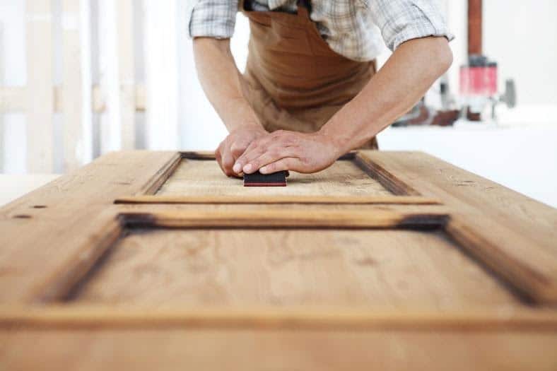 A wooden door is sanded and prepared for installation